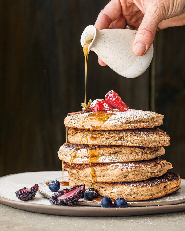 hand drizzling syrup over vegan pancake example of plant-based brunch